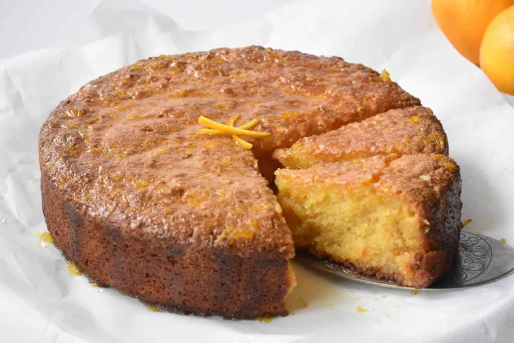 Whole orange cake with two slices cut.