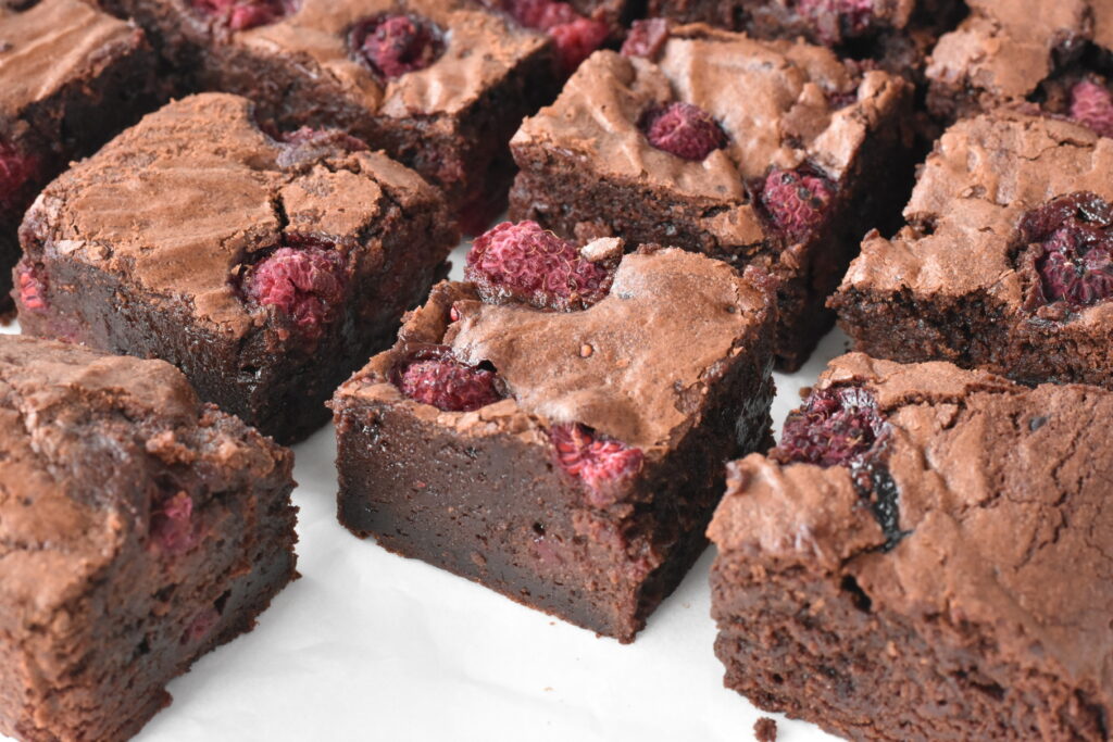 Raspberry brownie squares on baking paper.