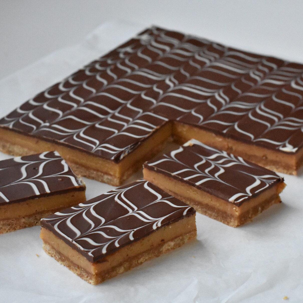 Caramel Slice with Marble Topping sliced on baking paper.