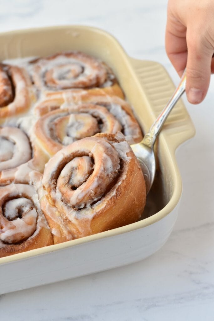 Cinnamon Roll being lifted out of tray