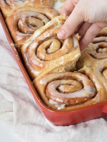 Cinnamon Roll being taken from the tray.