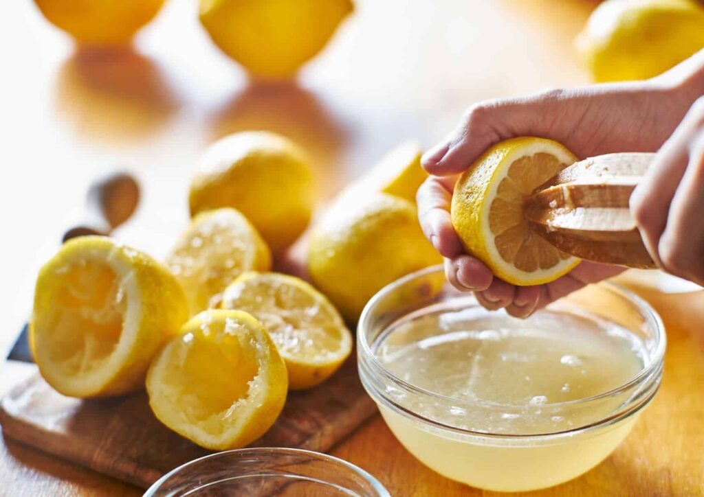 Hand juicing lemons into bowl.