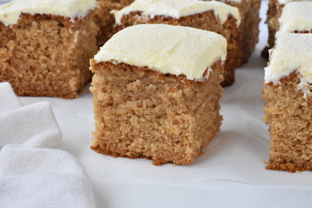 Square of spice cake with frosting on baking paper.