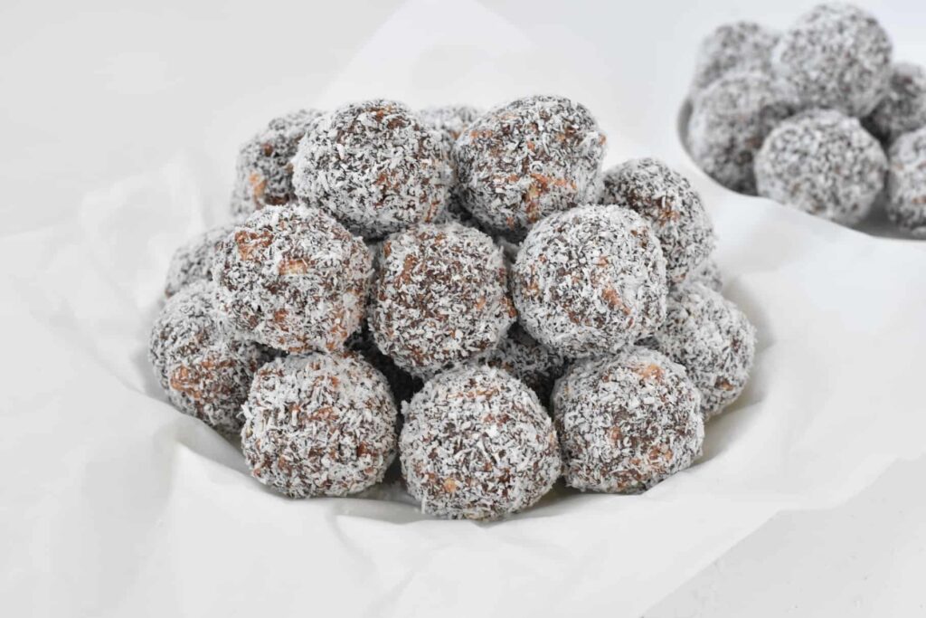 Bowl of rum balls stacked on white plate.