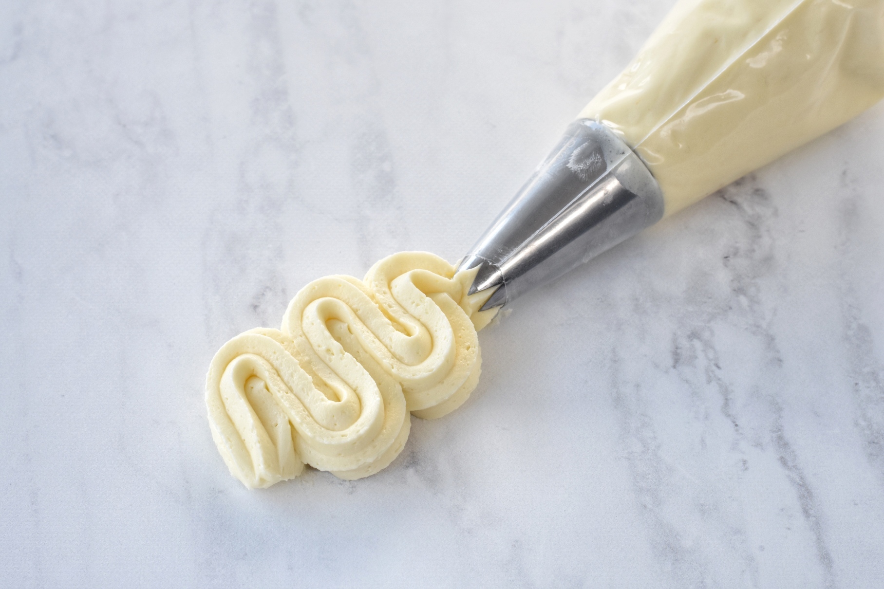 Buttercream being piped onto marble.