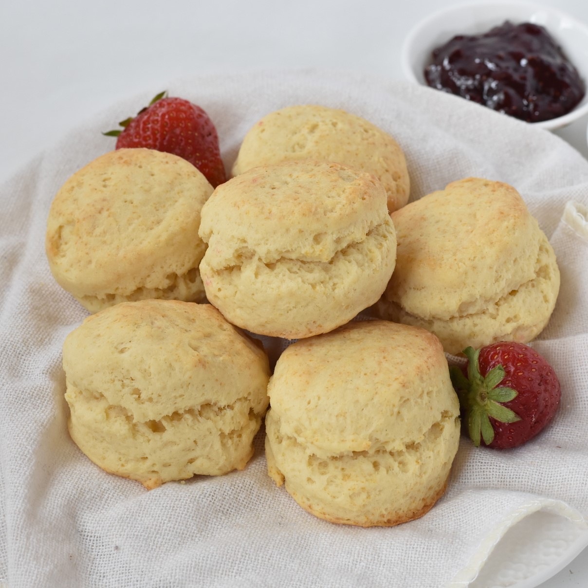 Scones stacked up on a plate with jam.