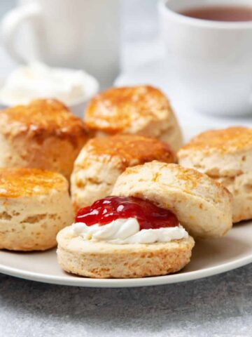Scones with jam and cream on plate.