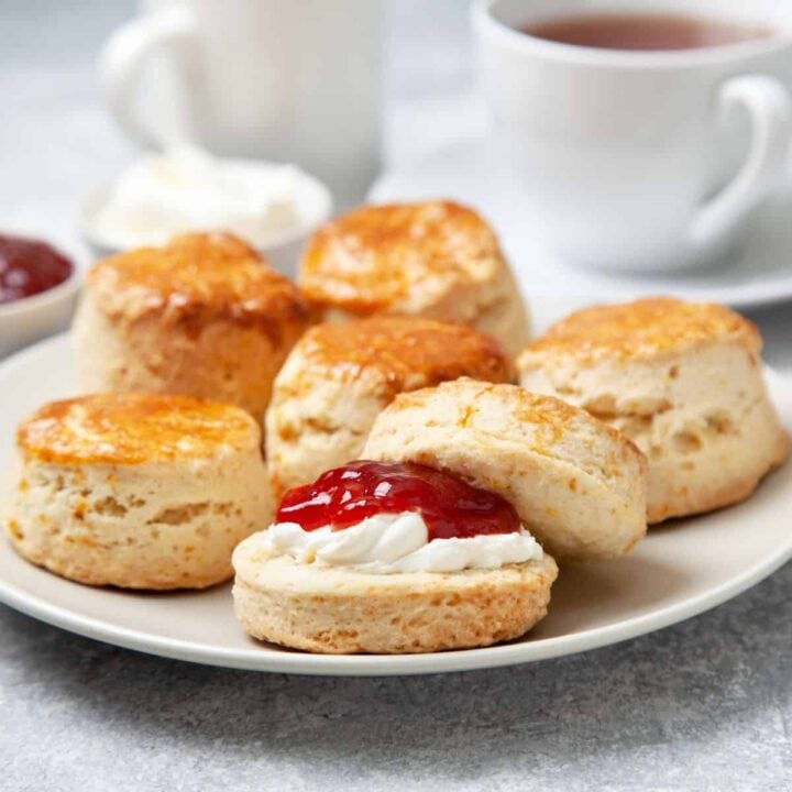 Scones with jam and cream on plate.