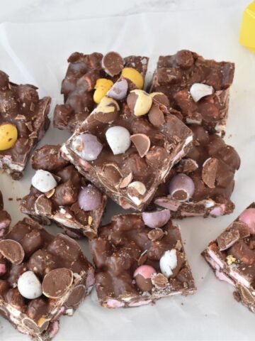 Squares of rocky road stacked on baking paper.