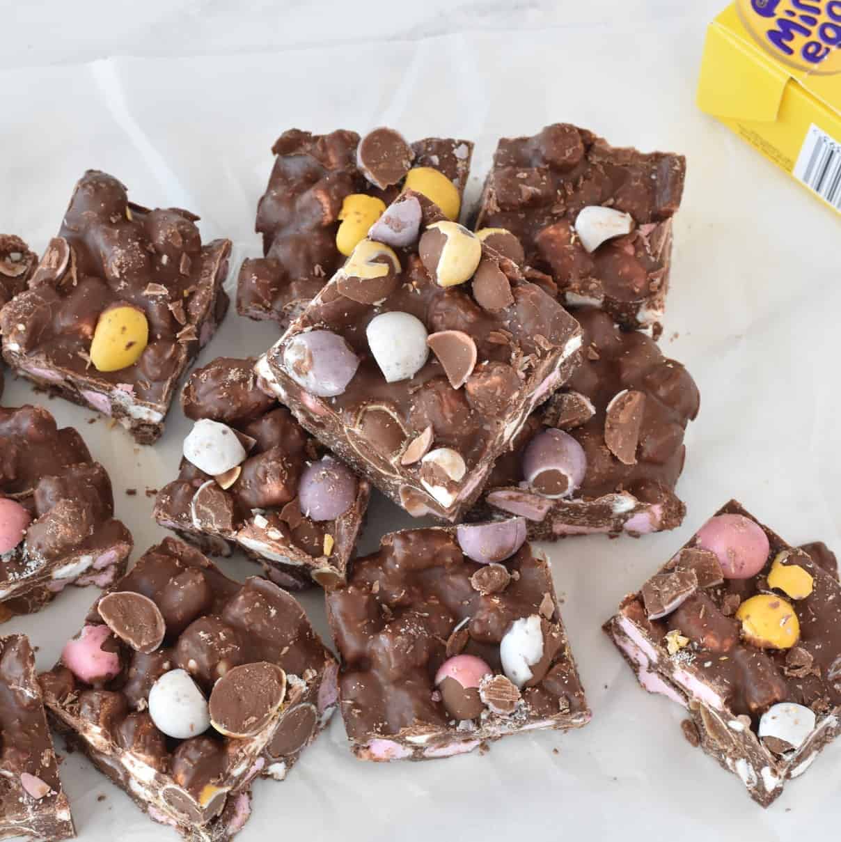 Squares of rocky road stacked on baking paper.