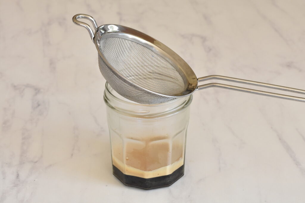 Strainer over jar with espresso shot.
