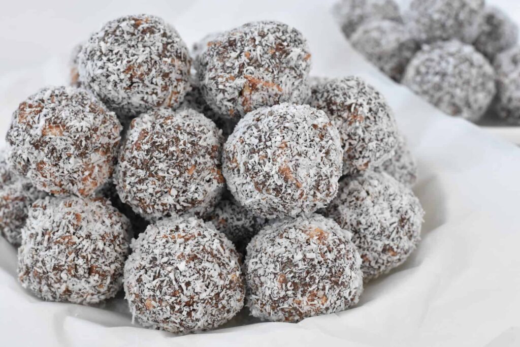Bowl of rum balls stacked on white plate.