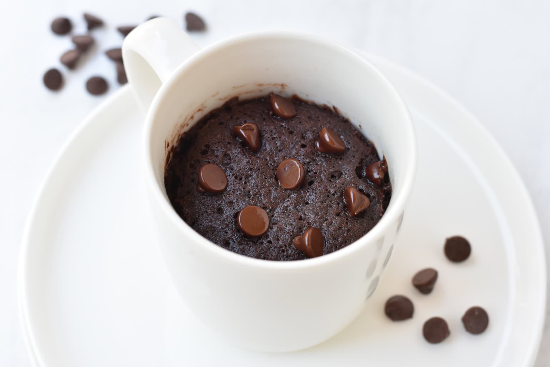 Chocolate mug cake in mug with choc chips sprinkled on top.