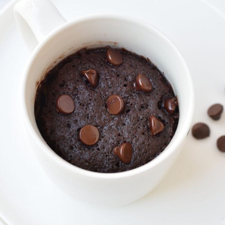 Chocolate cake in a mug with chocolate chips on top.