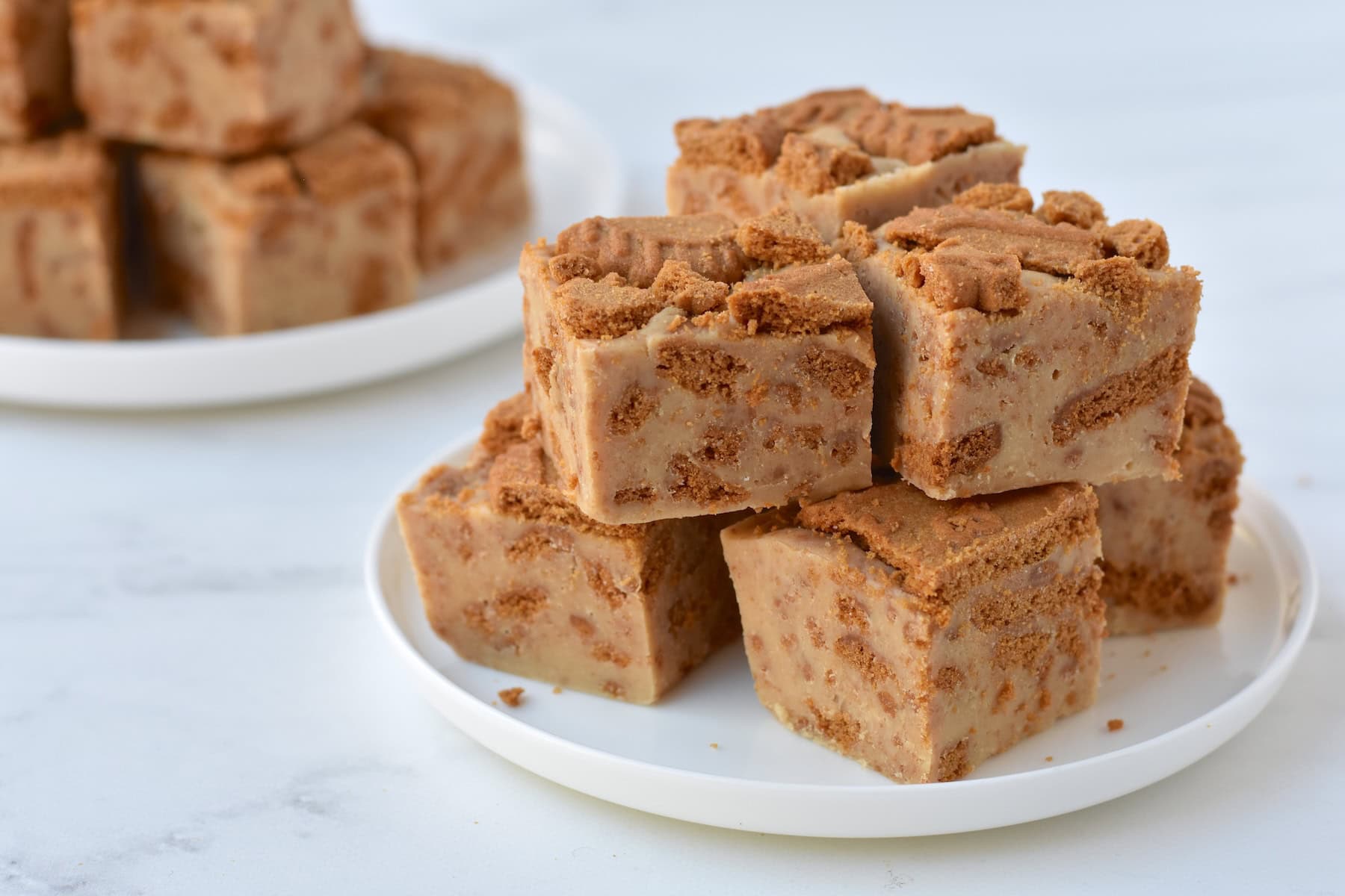 Squares of Biscoff fudge stacked on a plate.