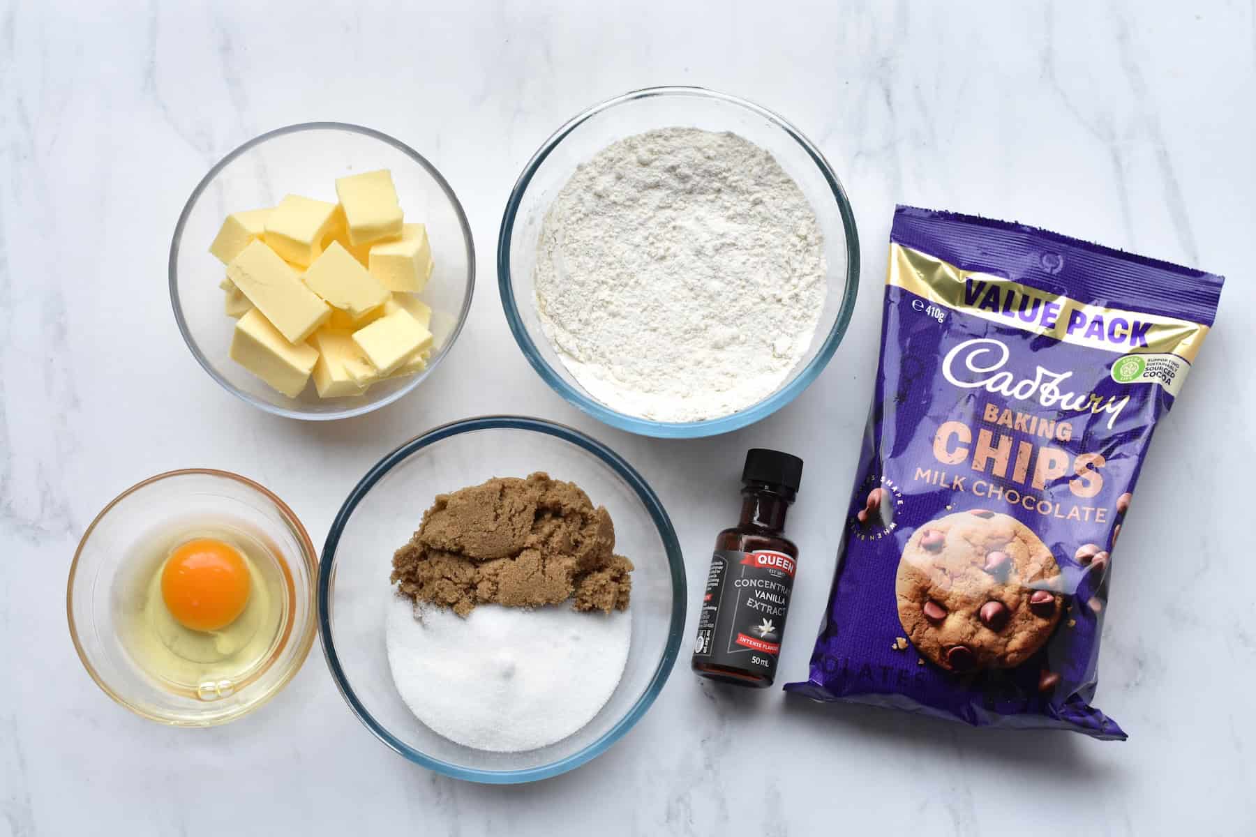Butter, egg, flour, sugars, vanilla and chocolate chips in separate containers.