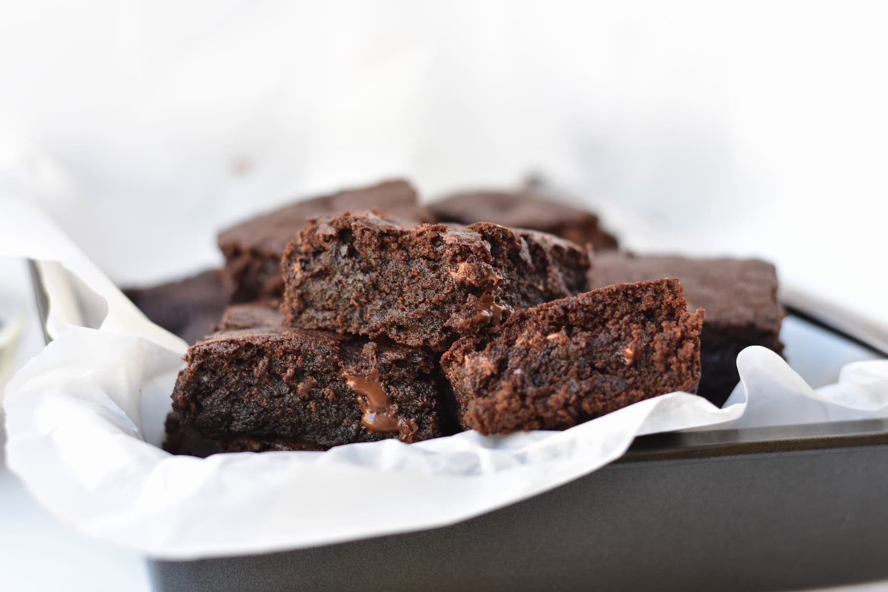 Brownies stacked in baking tray.