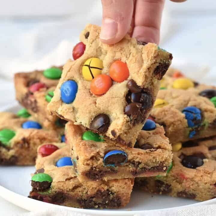 Square of cookie bar being picked up off plate.