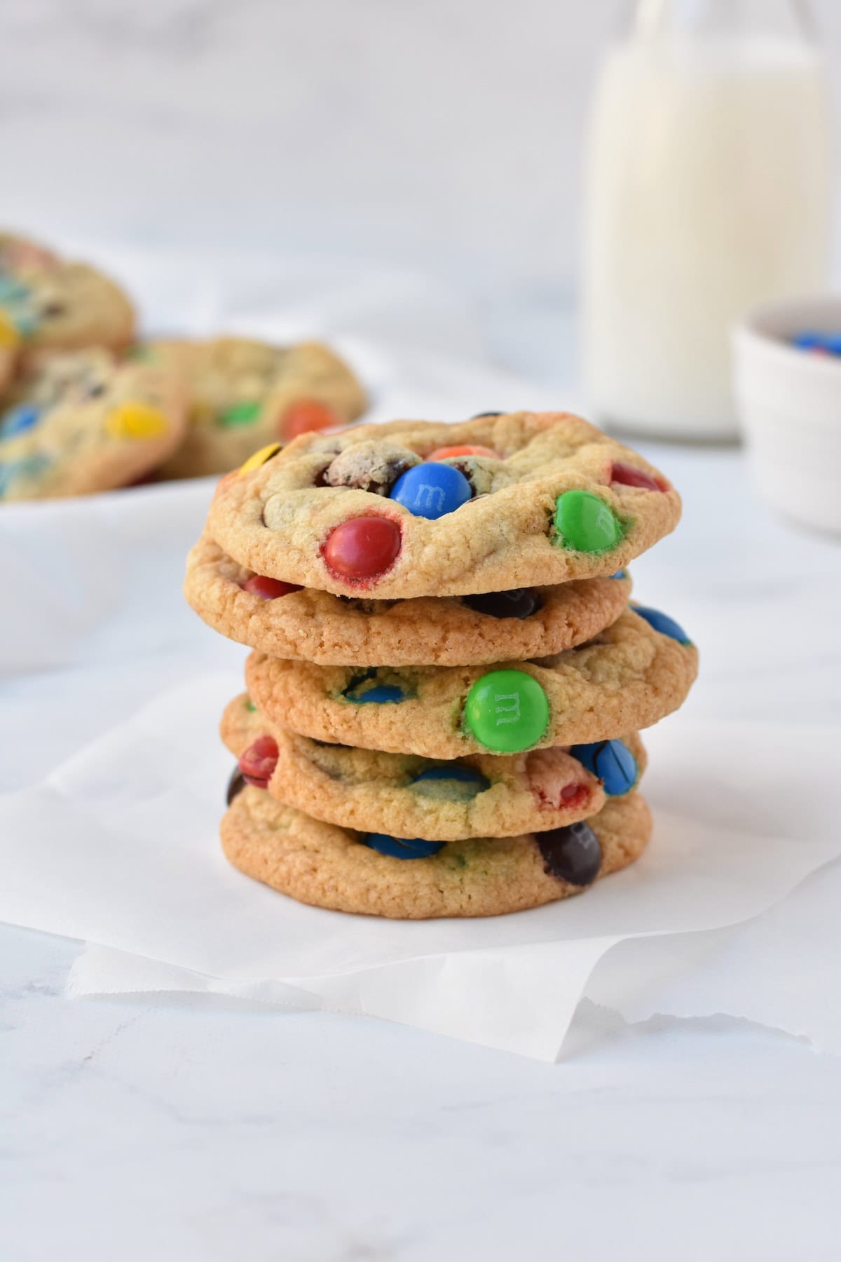 Stack of M&M cookies on baking paper.