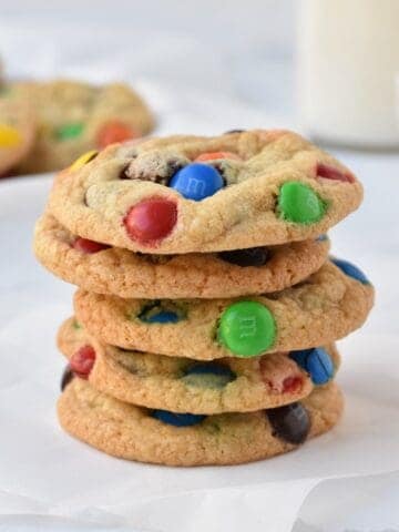 Stack of M&M cookies on baking paper.
