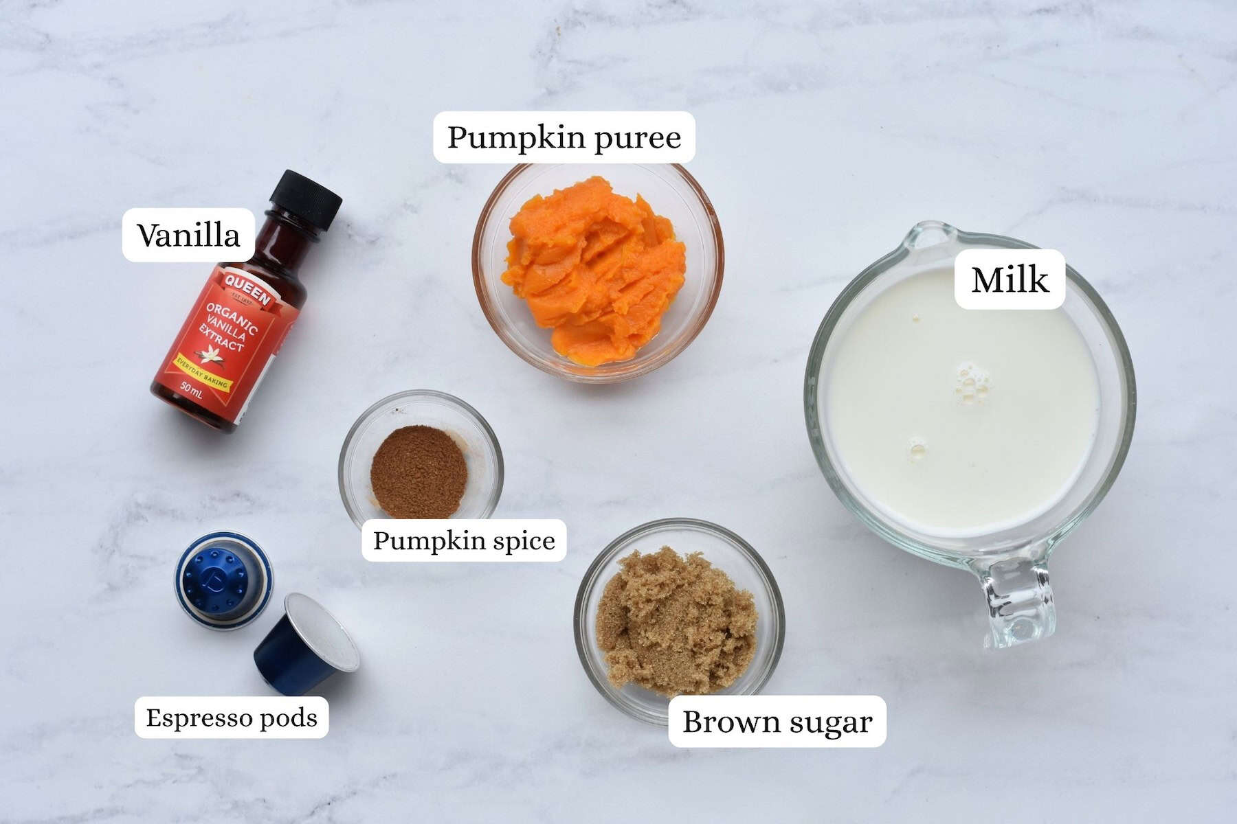 Pumpkin spice latte ingredients laid out on marble benchtop from above.