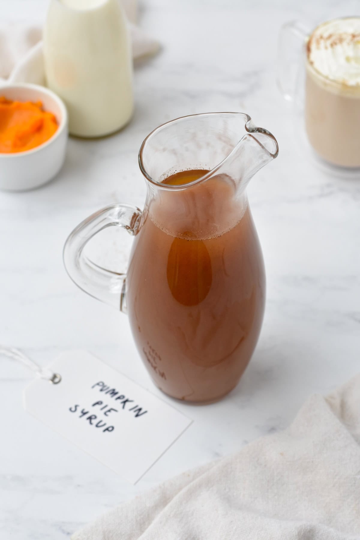 Pumpkin spice syrup in pouring jug with a label next to it.